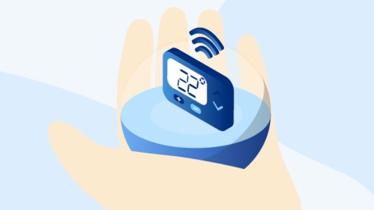 A Netatmo smart thermostat held in a hand