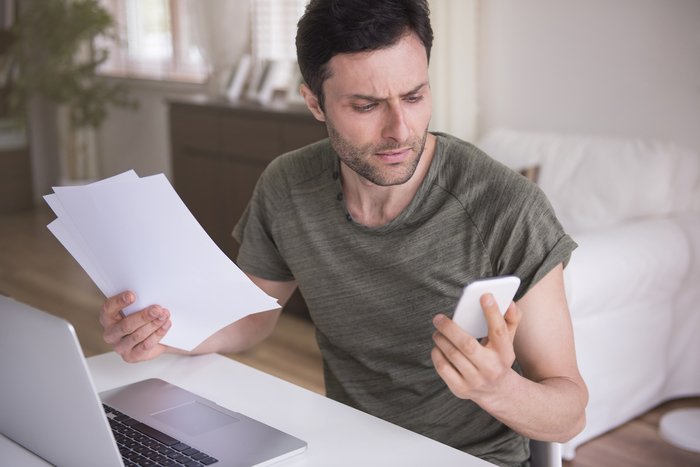 Man looking at bills holding a phone